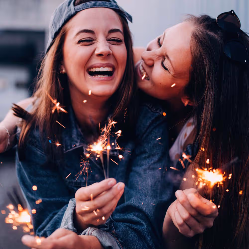 Foto zwei Freundinnen feiern mit brennenden Wunderkerzen Geburtstag
